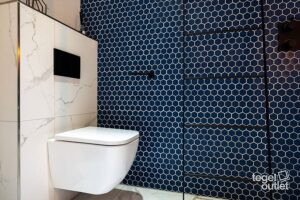 Toilettes avec une mosaïque hexagonale bleue au mur et des carreaux blancs effet marbre