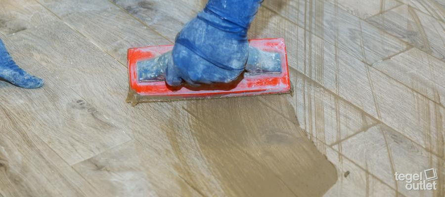 Le voile de ciment est retiré d'un carreau effet bois avec un tampon abrasif