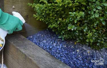 EasiHold spuiten op blauw grind in een border langs een houten balk