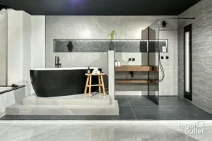 Salle de bains avec baignoire îlot noire et grands carreaux gris dans un showroom